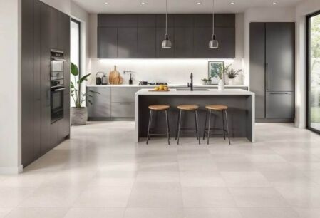 Modern kitchen with neutral-toned porcelain floor tiles, featuring a stylish island, dark cabinetry, and pendant lighting – best kitchen floor tiles for durability and design