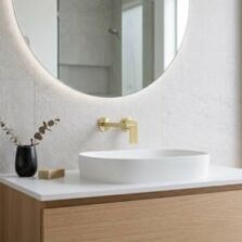 A luxury brushed gold two-piece basin tap set featuring a spout and mixer installed on a modern timber vanity.