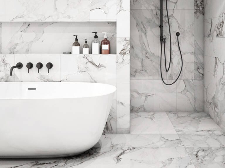Luxurious marble bathroom with black wall-mounted 3 peice mixer tap set over bath