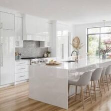 Bright modern white kitchen with stainless steel cabinet handles, marble-look island benchtop, and light timber flooring in Perth home