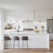 Modern white kitchen with sleek cabinetry and minimalist design, illustrating a practical kitchen cabinet buying guide for homeowners