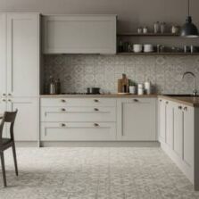 A modern kitchen featuring patterned tile ideas with a matching splashback and floor design in soft neutral tones, complemented by wooden countertops, matte cabinetry, and black pendant lighting.