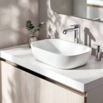 Modern white above-counter bathroom sink with chrome tapware on light timber vanity in bright Perth bathroom