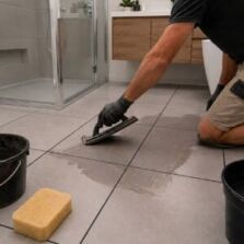 DIY renovator applying grout to floor tiles with a rubber grout float
