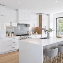 Modern kitchen cabinets for sale with gloss doors, chrome handles, grey tiled splashback, and marble-look island bench in Perth home
