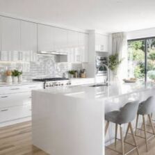 Modern white kitchen featuring gloss cabinets, sleek cupboards, and a large island bench with bar stools, showcasing contemporary Perth kitchen design