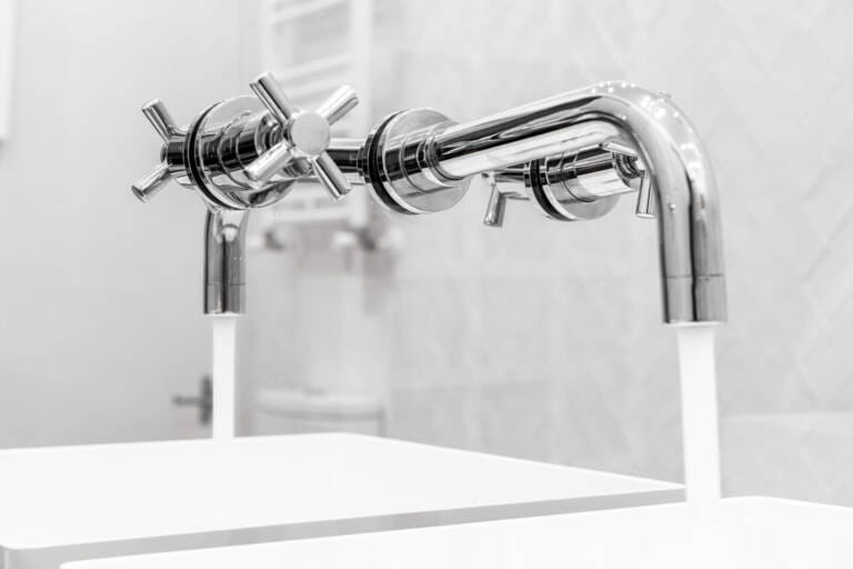 Close-up of modern chrome wall tapware installed above twin sinks in a bathroom