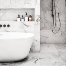 Luxurious marble bathroom with black wall-mounted 3 peice mixer tap set over bath