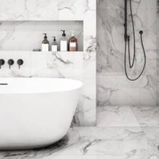 Luxurious marble bathroom with black wall-mounted 3 peice mixer tap set over bath