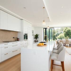 Modern white kitchen showcasing flat pack style cabinetry with island and seating