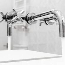 Close-up of modern chrome wall tapware installed above twin sinks in a bathroom